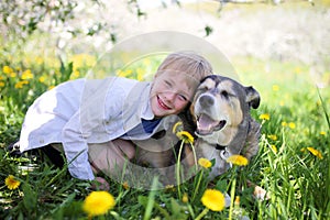 Happy Little Boy Relaxing in Flower Meadow and Hugging his Pet D