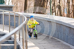 Happy little boy riding a run-bike in the park