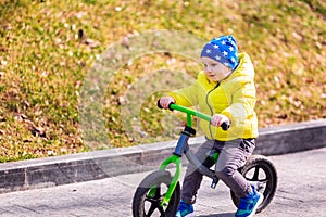 Happy little boy riding a run-bike in the park