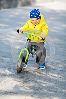 Happy little boy riding a run-bike in the park