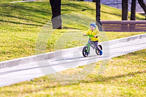 Happy little boy riding a run-bike in the park