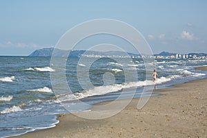 Happy little boy running far away in water along the sea beach