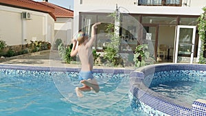 happy little boy running and jumping in swimming pool, child having fun, splashing water. Summer travel family hotel