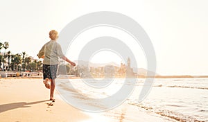 Happy little boy running by Mediterranean spain coast in Sitges town near Barcelona