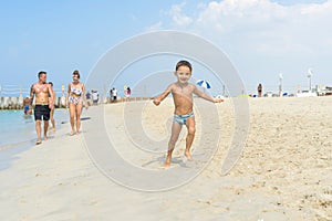 Happy little boy running on sand tropical beach. Positive human emotions, feelings, joy. Funny cute child making vacations and enj