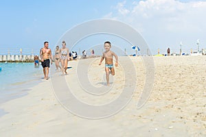 Happy little boy running on sand tropical beach. Positive human emotions, feelings, joy. Funny cute child making vacations and enj