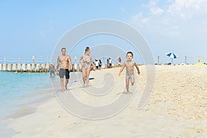 Happy little boy running on sand tropical beach. Positive human emotions, feelings, joy. Funny cute child making vacations and enj