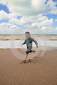 Happy little boy running at the sea coast