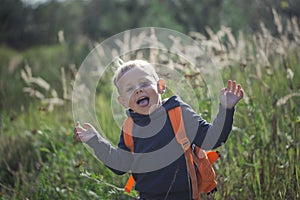 A happy little boy runs along a forest path