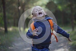 A happy little boy runs along a forest path