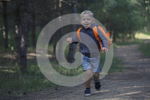A happy little boy runs along a forest path