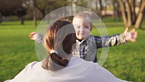 Happy little boy runs into mother`s open armsa nd hugs her in spring park