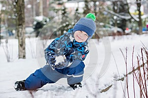 Happy little boy sculpts snowballs