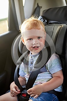 Happy little boy sits in a car seat