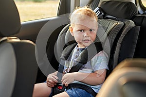 Happy little boy sits in a car seat