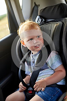 Happy little boy sits in a car seat