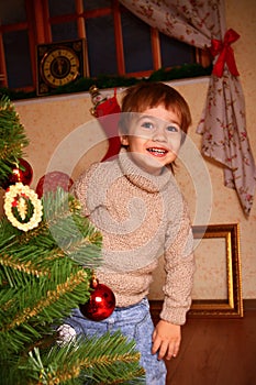 Happy little boy standing near the Christmas tree