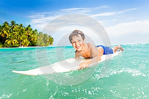 Happy little boy swim on surfing board in the sea