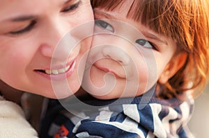 Happy little boy tenderly leaning to his mom