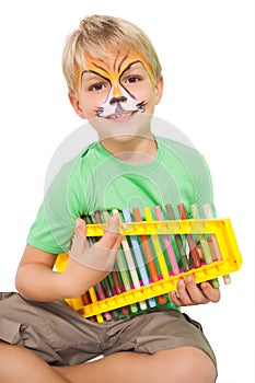 Happy little boy in tiger face paint playing xylophone