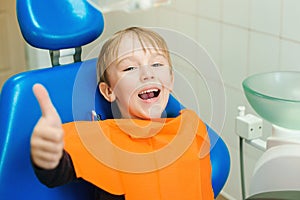 Happy little boy visiting dentist. Child sitting in a blue chair dental. Examining little boy`s teeth in dental clinic