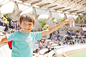 Happy little boy waving hand on stadium and smile