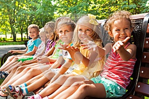 Happy little boys and girls on the bench in park