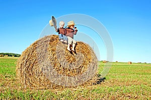 Happy Little Boys Sitting on Big Hay Bale in Farm Field