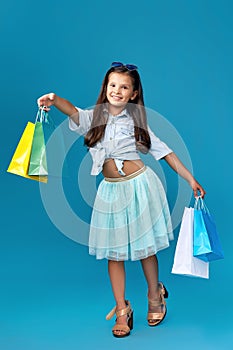 happy little caucasian child girl holds many shopping bags