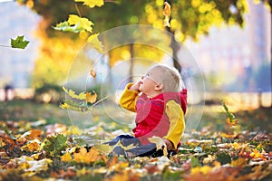 Happy little child, baby boy, laughing and playing in the autumn