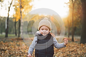 Happy little child baby boy laughing and playing in the autumn day