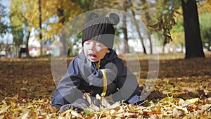 Happy little child, baby boy laughing and playing in the autumn in the park walk outdoors.