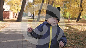 Happy little child, baby boy laughing and playing in the autumn in the park walk outdoors.