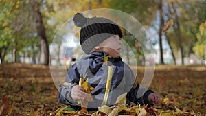 Happy little child, baby boy laughing and playing in the autumn in the park walk outdoors.