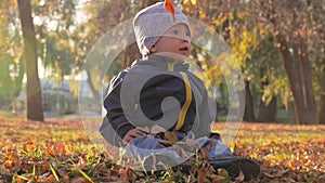 Happy little child, baby boy laughing and playing in the autumn in the park walk outdoors.