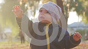 Happy little child, baby boy laughing and playing in the autumn in the park walk outdoors.