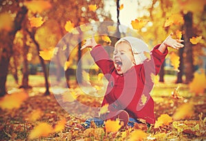 Happy little child, baby girl laughing and playing in autumn