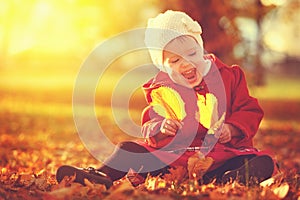 Happy little child, baby girl laughing and playing in autumn