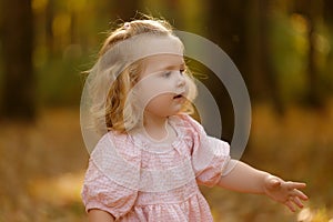 happy little child, baby girl laughing and playing in the autumn on the nature walk outdoors