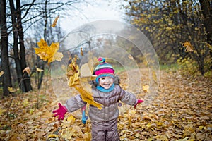 Happy little child, baby girl laughing and playing leaves in the autumn on the nature walk outdoors