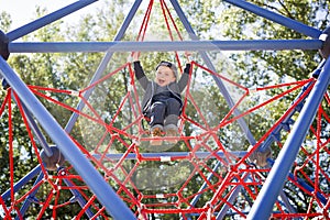 Happy little child boy climbed on playground