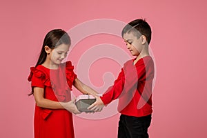 Happy little child boy gives smiling girl a gift box