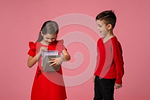 Happy little child boy gives smiling girl a gift box