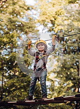 Happy little child climbing on a rope playground outdoor. Cute baby boy playing. Hike and kids concept. Active children