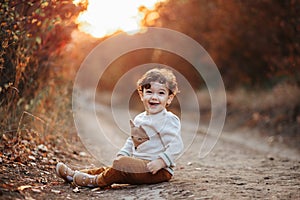 Happy little child, curly hair baby boy laughing and playing in the autumn on the nature walk outdoors