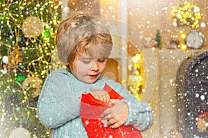 Happy little child dressed in winter clothing think about Santa near Christmas tree. Christmas kids - happiness concept