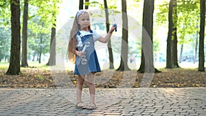 Happy little child girl blowing soap bubbles outside in green park. Outdoor summer activities for children concept