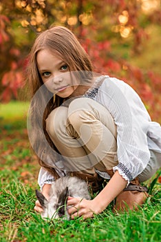 Happy little child girl with cute rabbit. Portrait of kid with pet