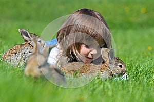 Happy little child girl with cute rabbit. Portrait of kid with pet. Outdoors.