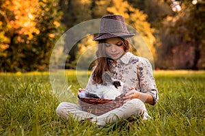 Happy little child girl with cute rabbit. Portrait of kid with pet. Outdoors